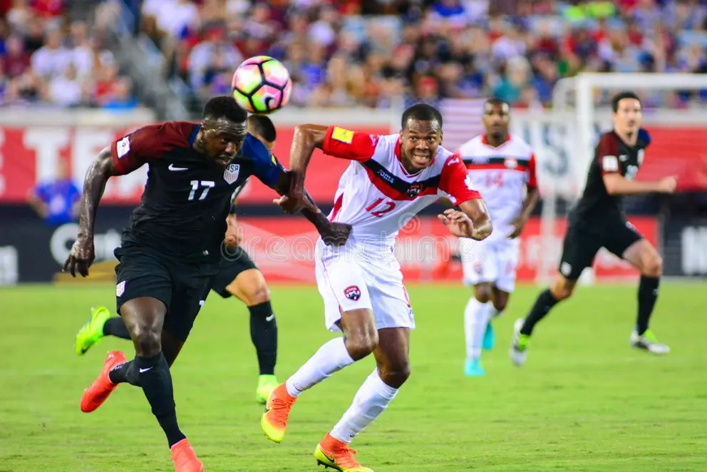 Jozy Altidore competing for a header in a dark United States number 17 kit